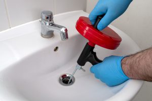 Plumber removing sink clog with a drain auger
