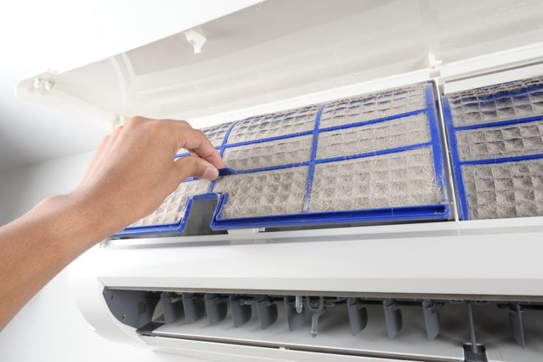 Photo of Larry & Sons air technician removing a dirty filter form an AC unit.